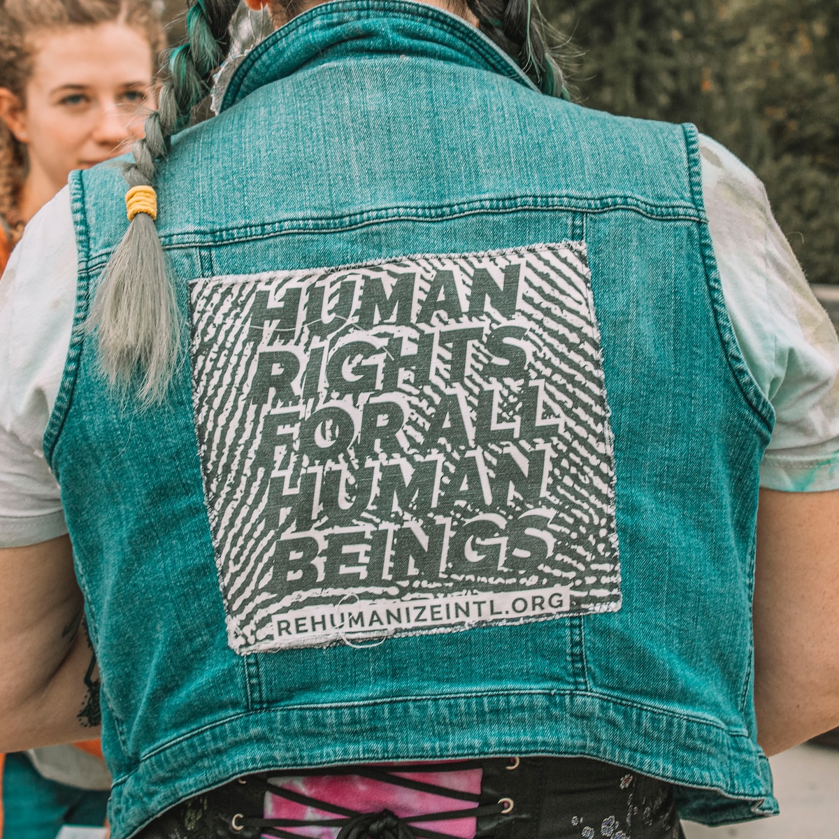 a woman wearing a denim vest with a human rights message - GRC AI autoclassification is a human rights issue